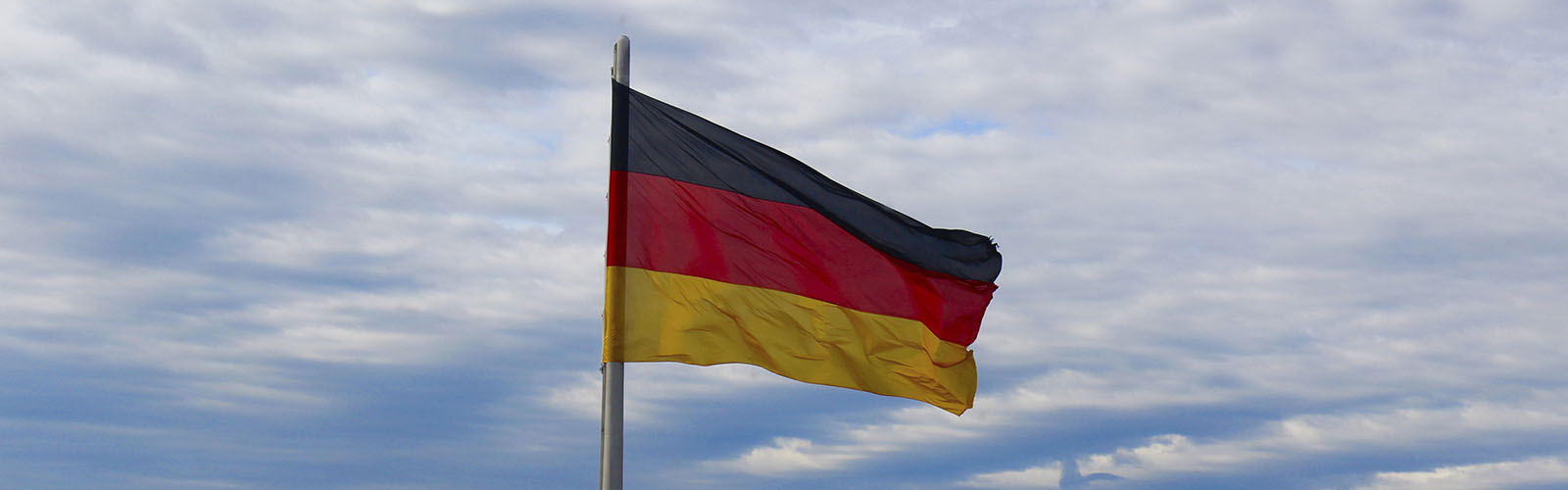 The German flag is waving in the wind. The clear sky is in the background.